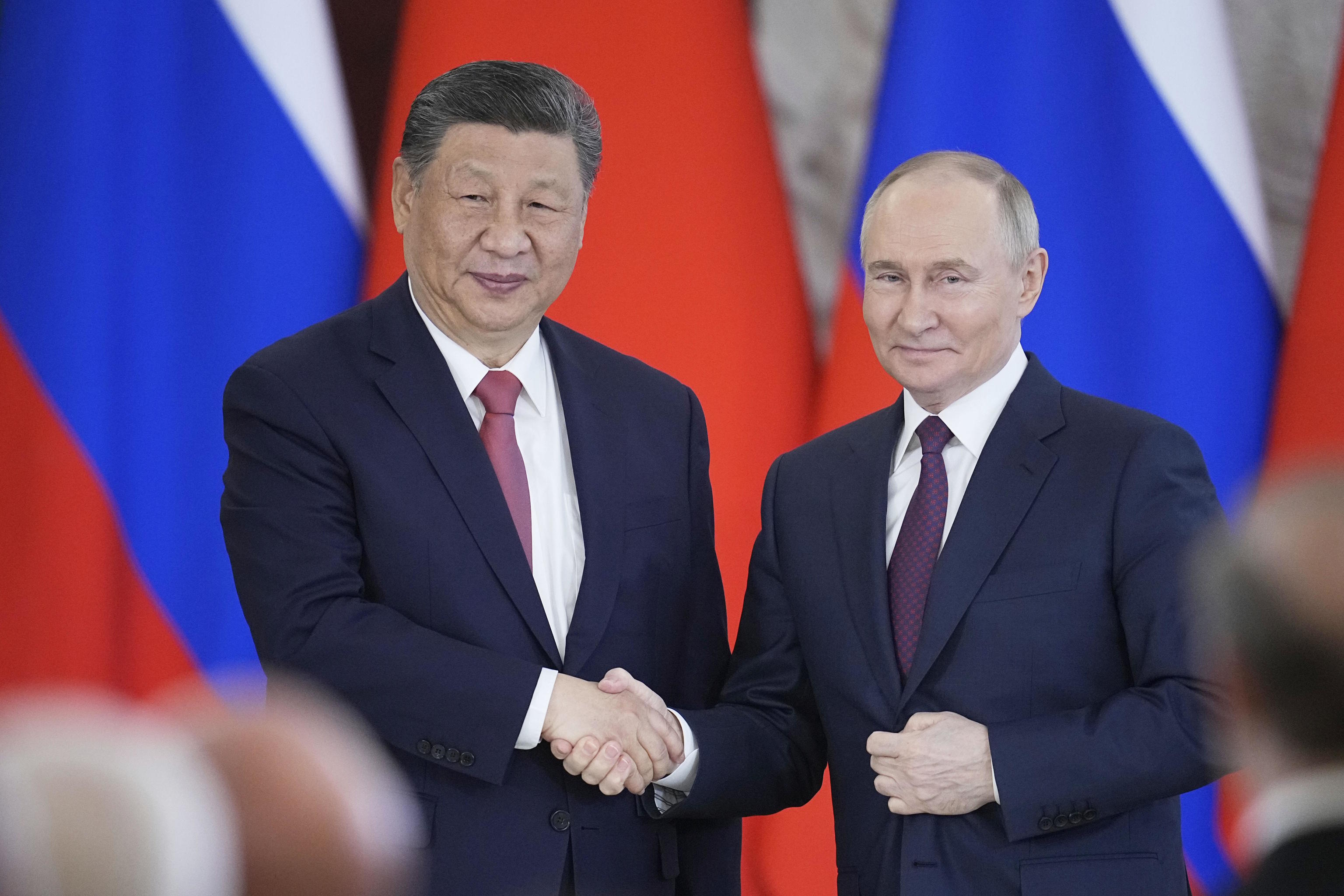 Vladimir Putin and Xi Jinping greet each other at the Kremlin.
