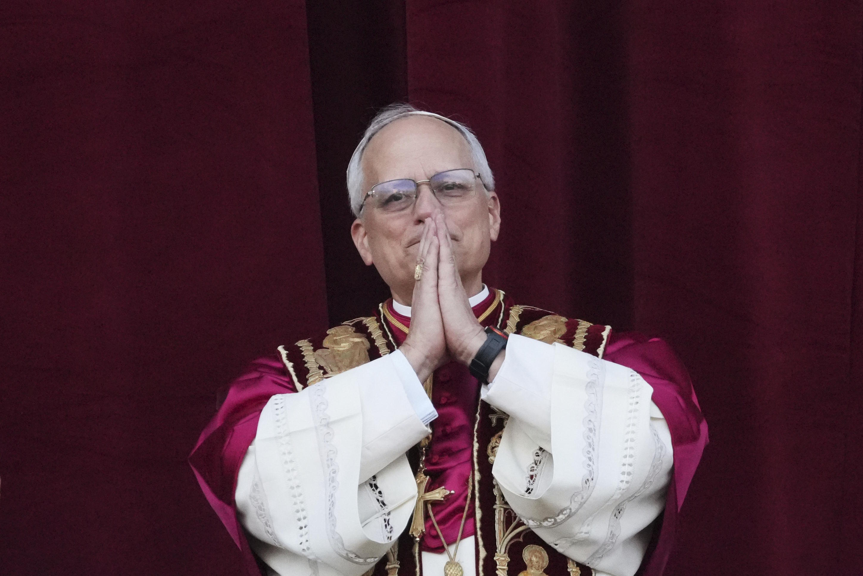 The new Pope Leo XIV joins his hands on the balcony of St. Peter's Basilica.