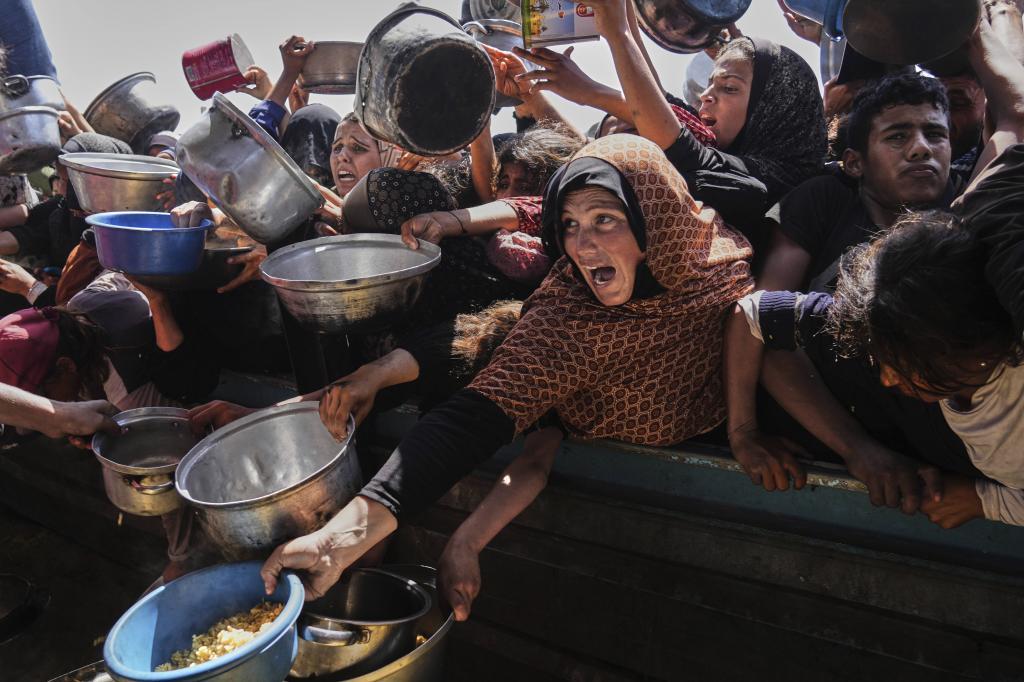 Palestinians struggle to obtain donated food at a community kitchen in Khan Younis