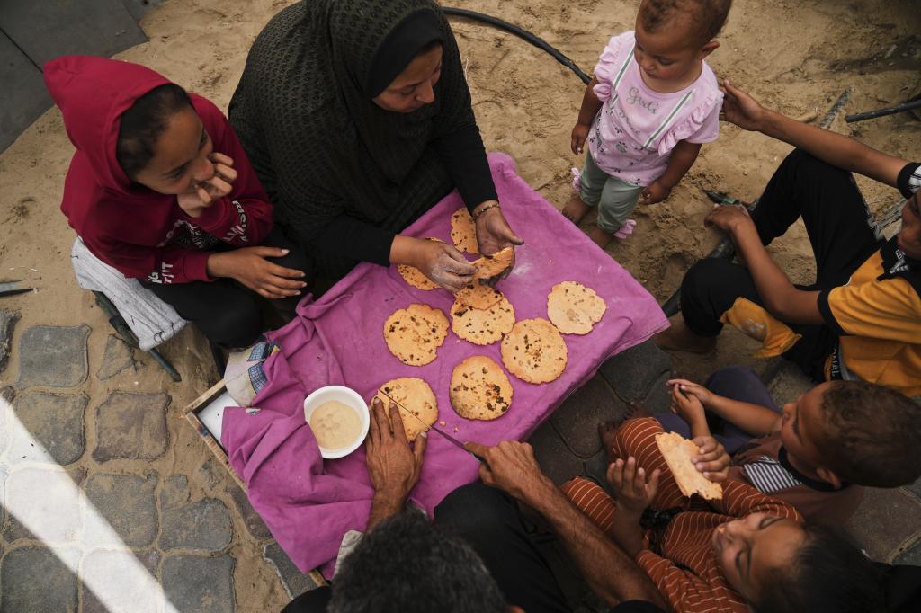 Nevin Qassim, a displaced Palestinian woman, and her family eat bread she baked from ground lentils as a substitute amid a flour shortage in the Gaza Strip