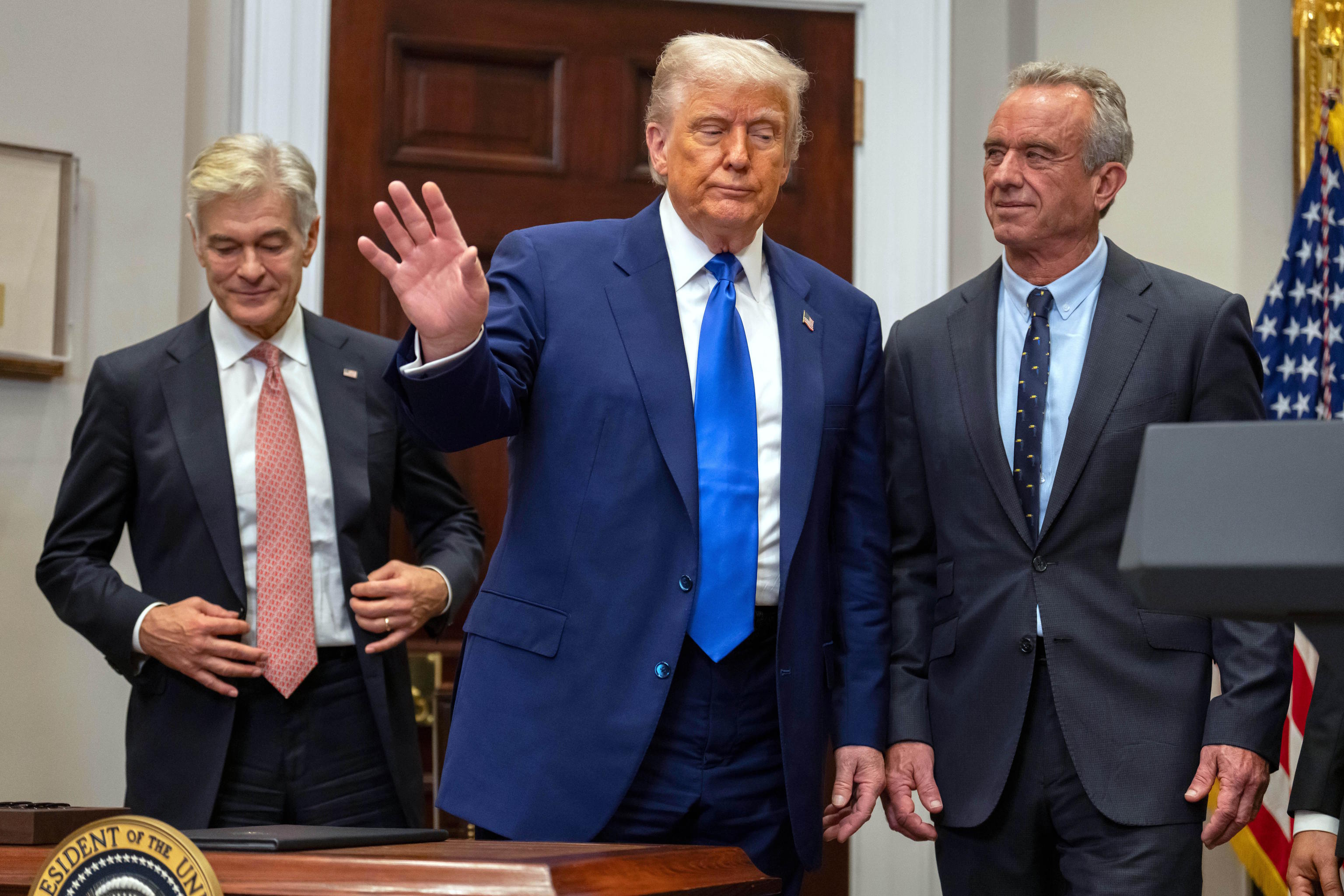 Trump gestures as he prepares to leave with Dr. Mehmet Oz, left, and R.F.K.