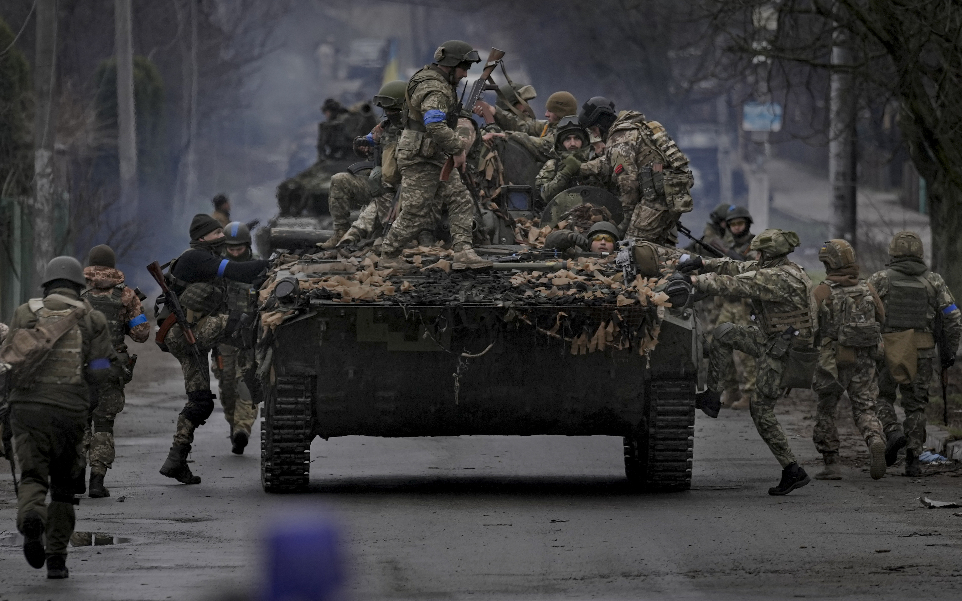 Ukrainian servicemen climb on a vehicle outside Kyiv, Ukraine.