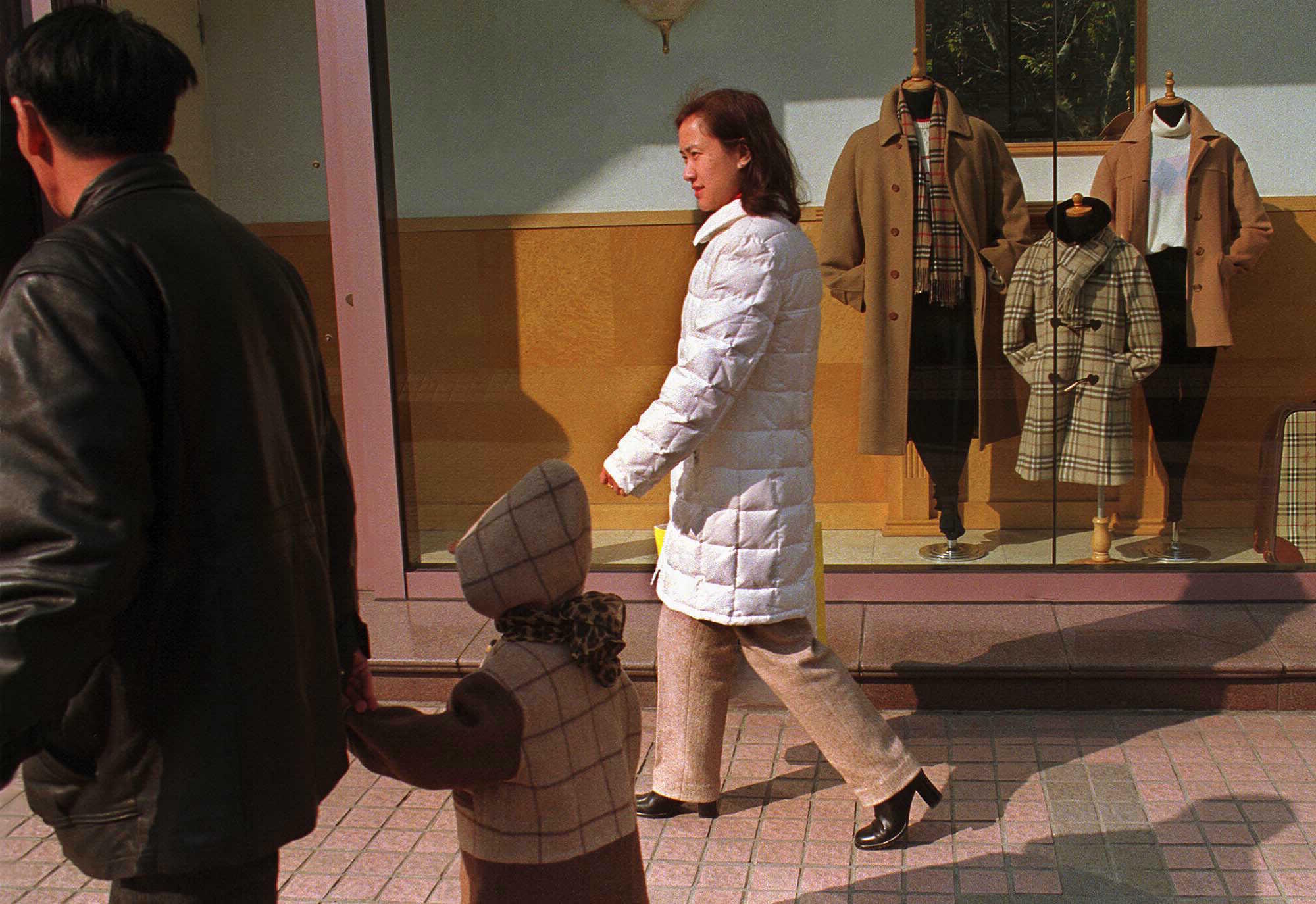 A typical Chinese family, a couple with a child, walks past a Burberry store.