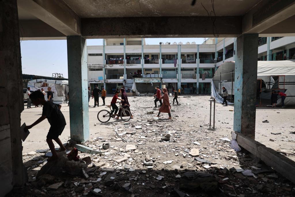 A Palestinian boy rides his bicycle over debris in the courtyard of an school.