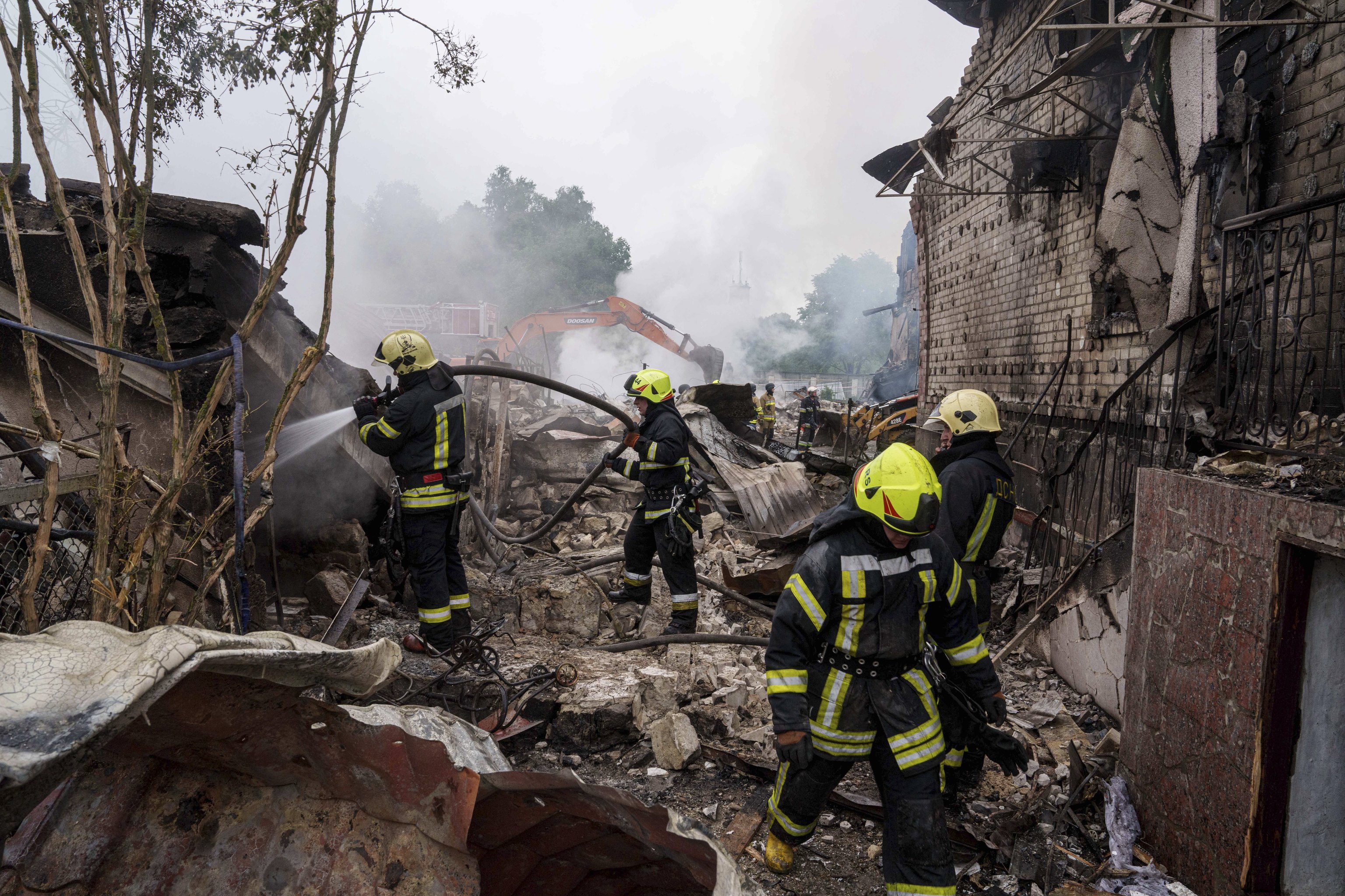 Rescue workers extinguish a fire of a house destroyed by a Russian strike in Markhalivka village, Kyiv.
