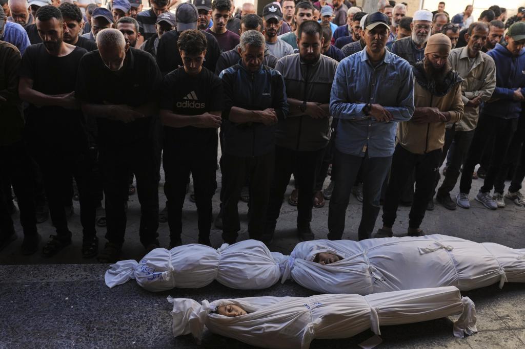 Palestinians pray over the bodies of their relatives who were killed in an Israeli army airstrike