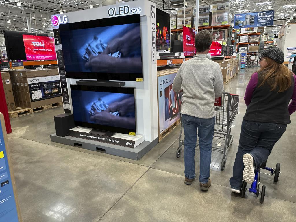 Shoppers pass by large-screen televisions on display in a Costco warehouse