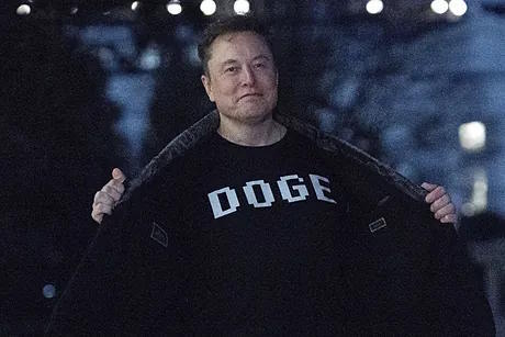 Elon Musk wears a DOGE t-shirt.