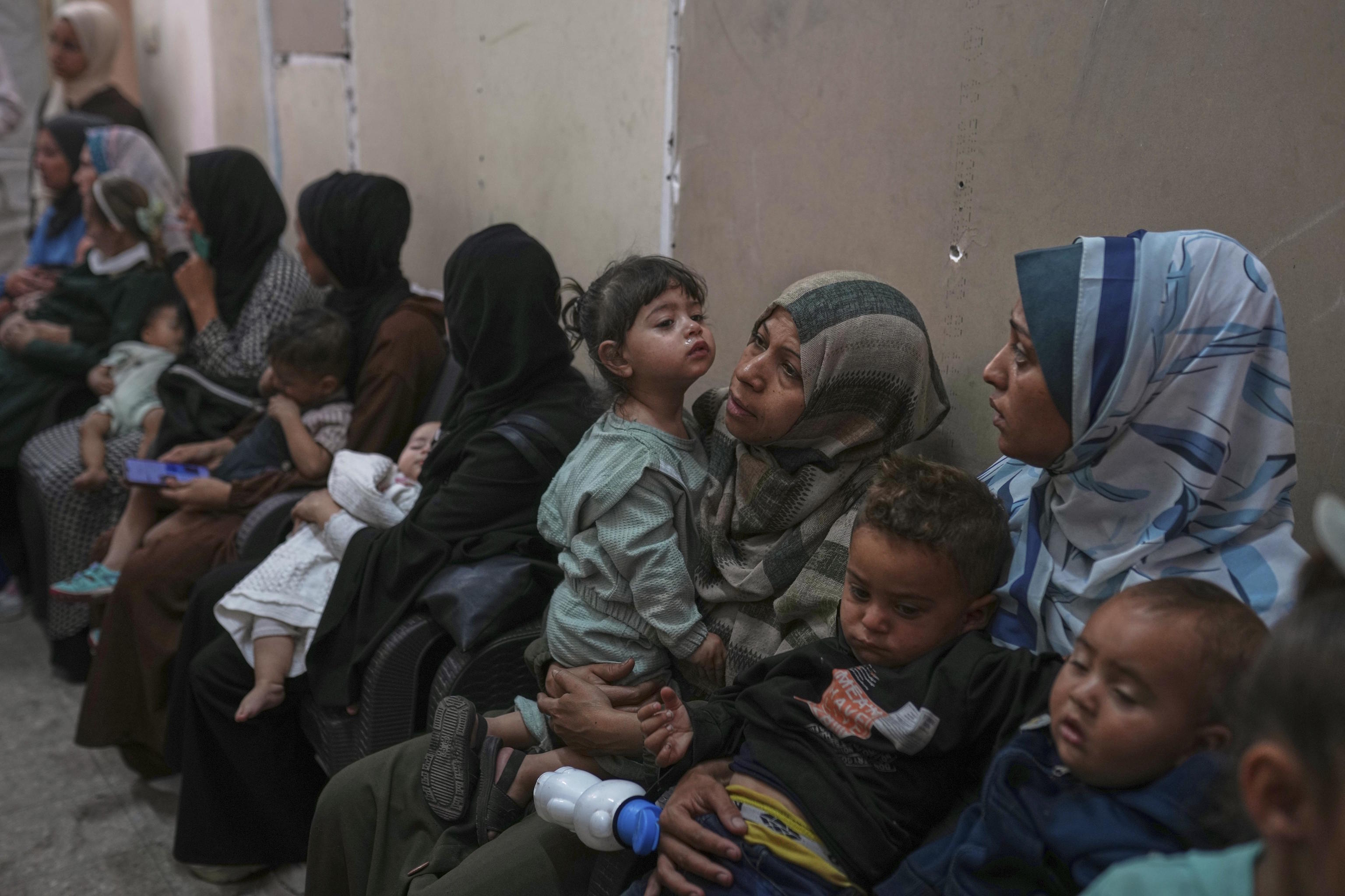 Palestinian women wait with their sick children for medical care in Gaza.