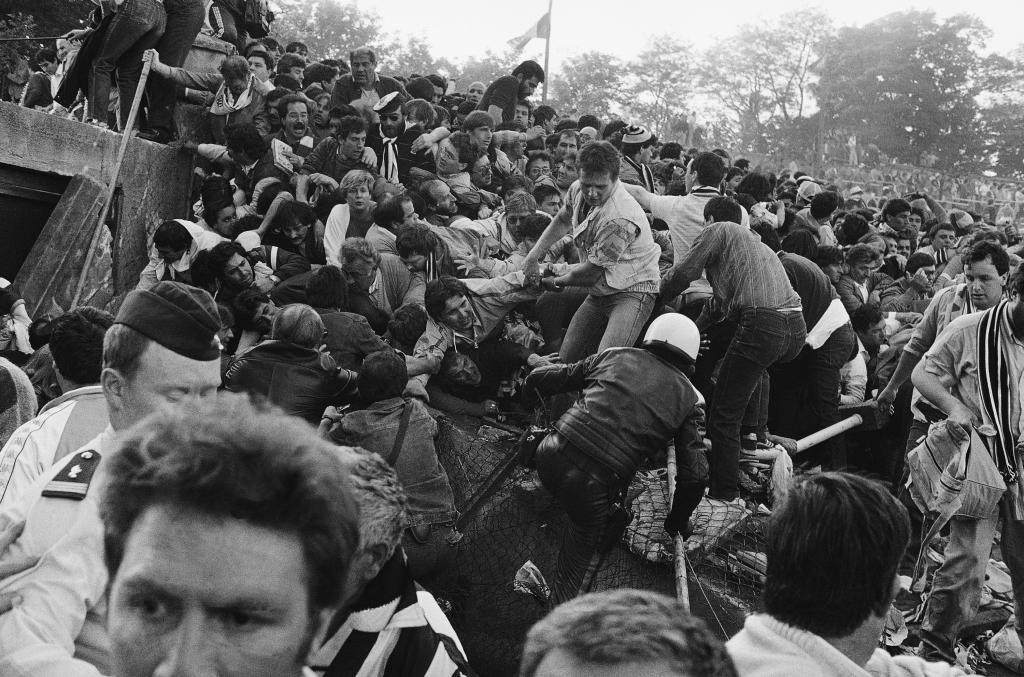 A crowd of soccer fans in the Brussels Heysel stadium, falls down in a heavy group over the broken fence just prior to the European Champion's Cup Final between Liverpool and Juventus of Turin, in Brussels