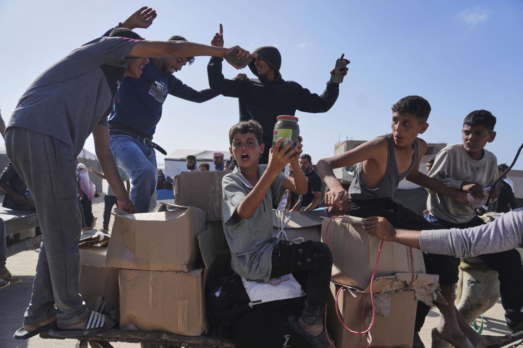 Palestinians carry boxes containing food and humanitarian aid packages delivered by the Gaza Humanitarian Foundation