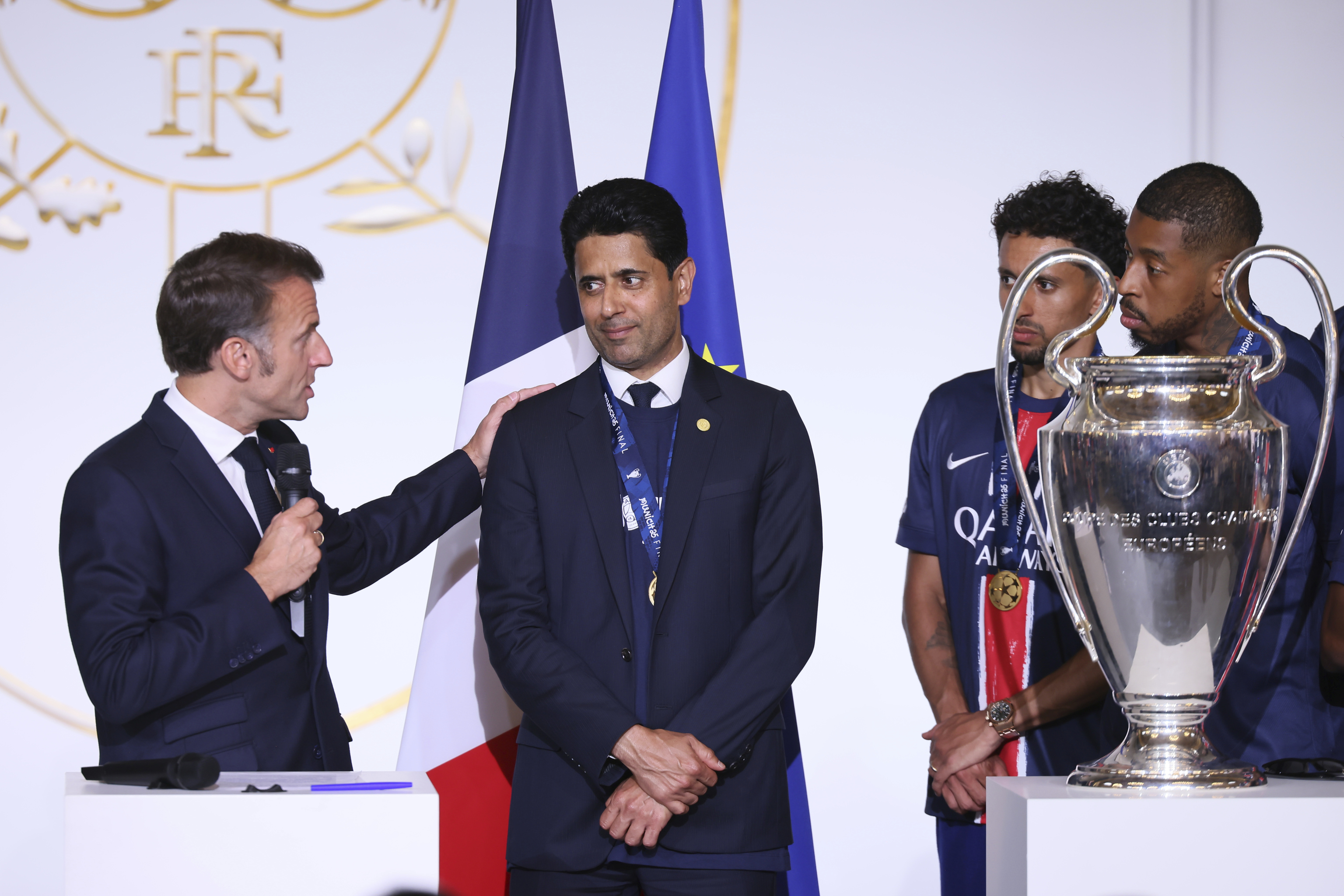 French President Emmanuel Macron gestures toward PSG president Nasser Al-Khelaifi, center.