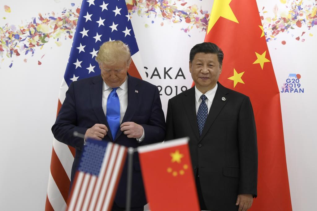 President Donald Trump adjusts his jacket as he poses for a photo with Chinese President Xi Jinping
