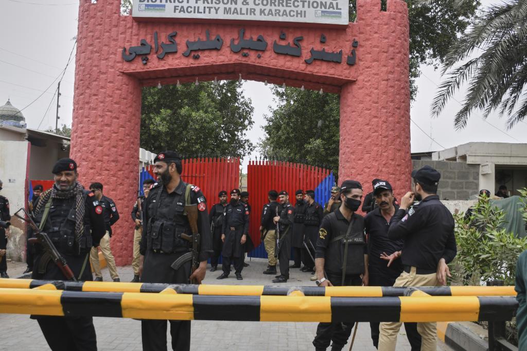 Police officer and paramilitary soldiers stand guard outside the district Malir prison,