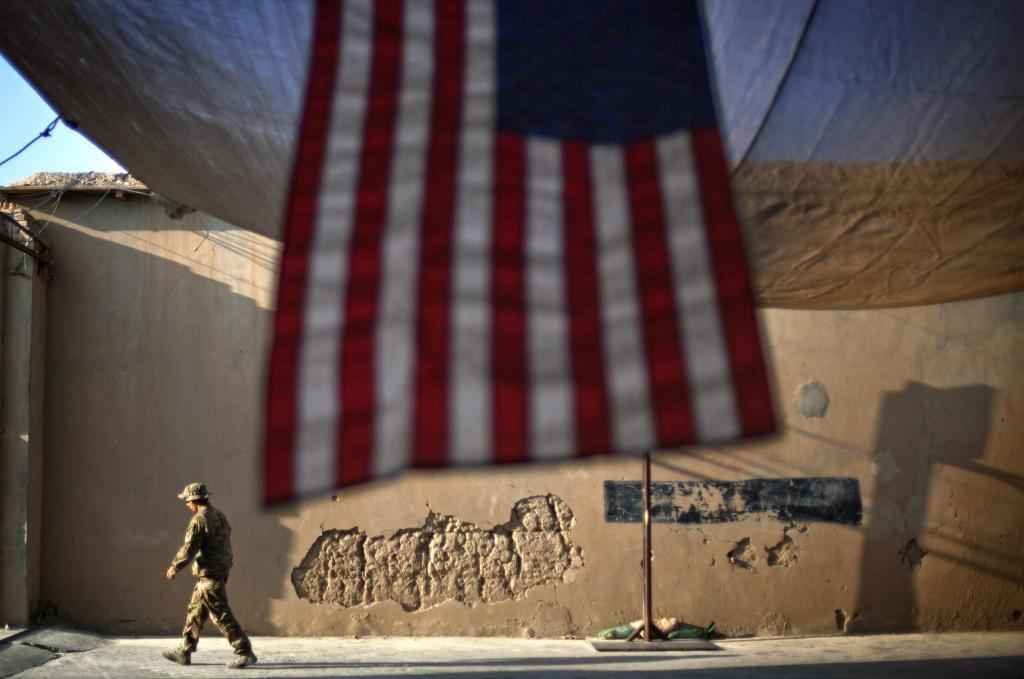 A U.S. Army soldier walks past an American Flag