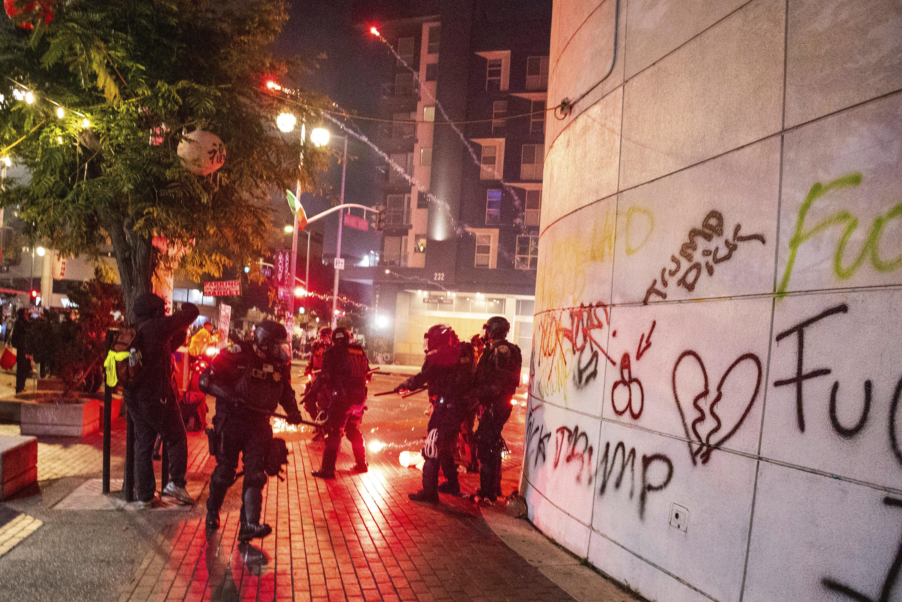 Police take cover from projectiles during protests.