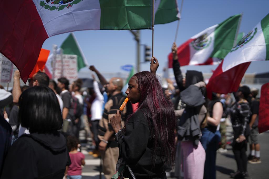 A protester cools down with an icicle while joining other protesters waving Mexican National Flags during a protest to denounce ICE