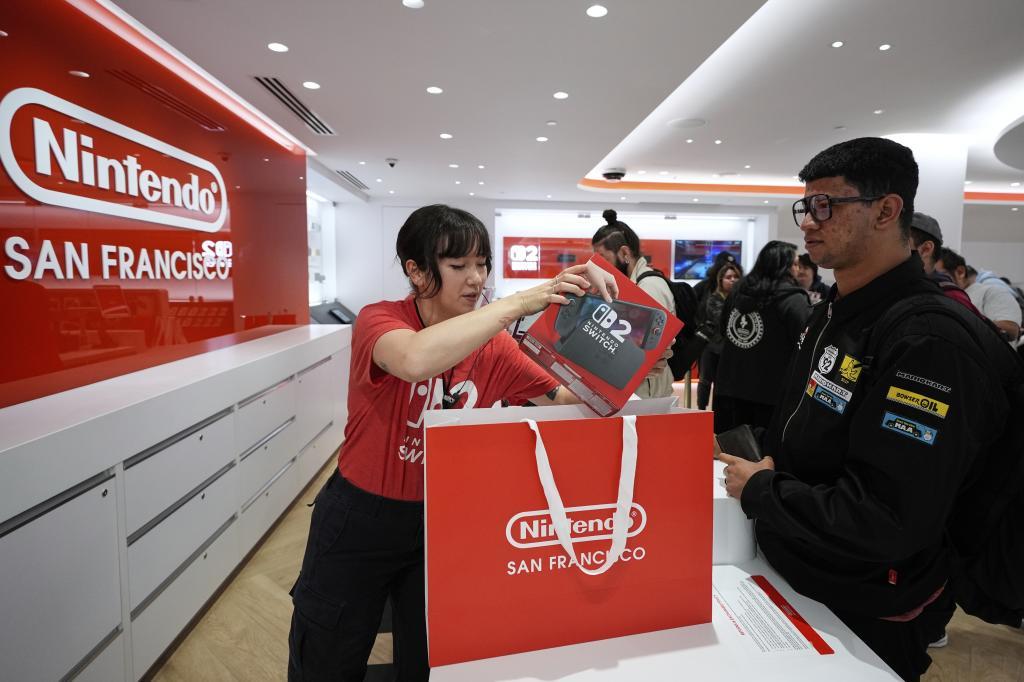 La embajadora especialista de Nintendo, Cyan Chang, a la izquierda, coloca una consola Nintendo Switch 2 dentro de una bolsa