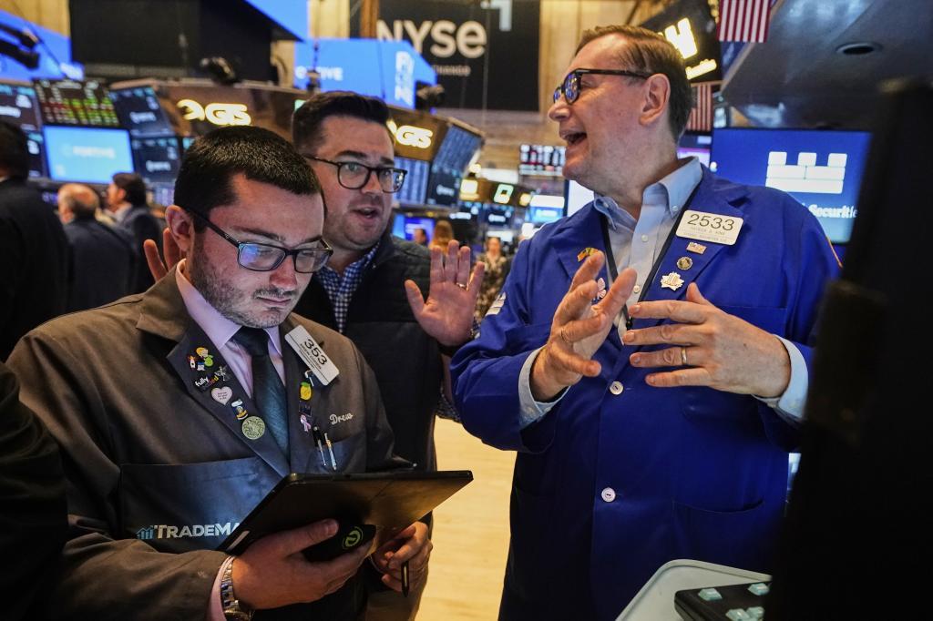 Traders Drew Cohen, left, and Joseph Lawler, center, work with specialist Patrick King on the floor of the New York Stock Exchange