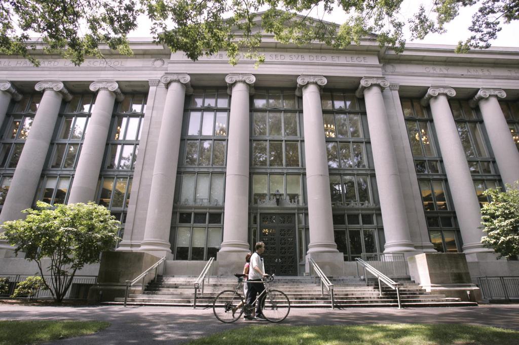 A bicyclist walks by Langdell Hall, the Harvard Law Library