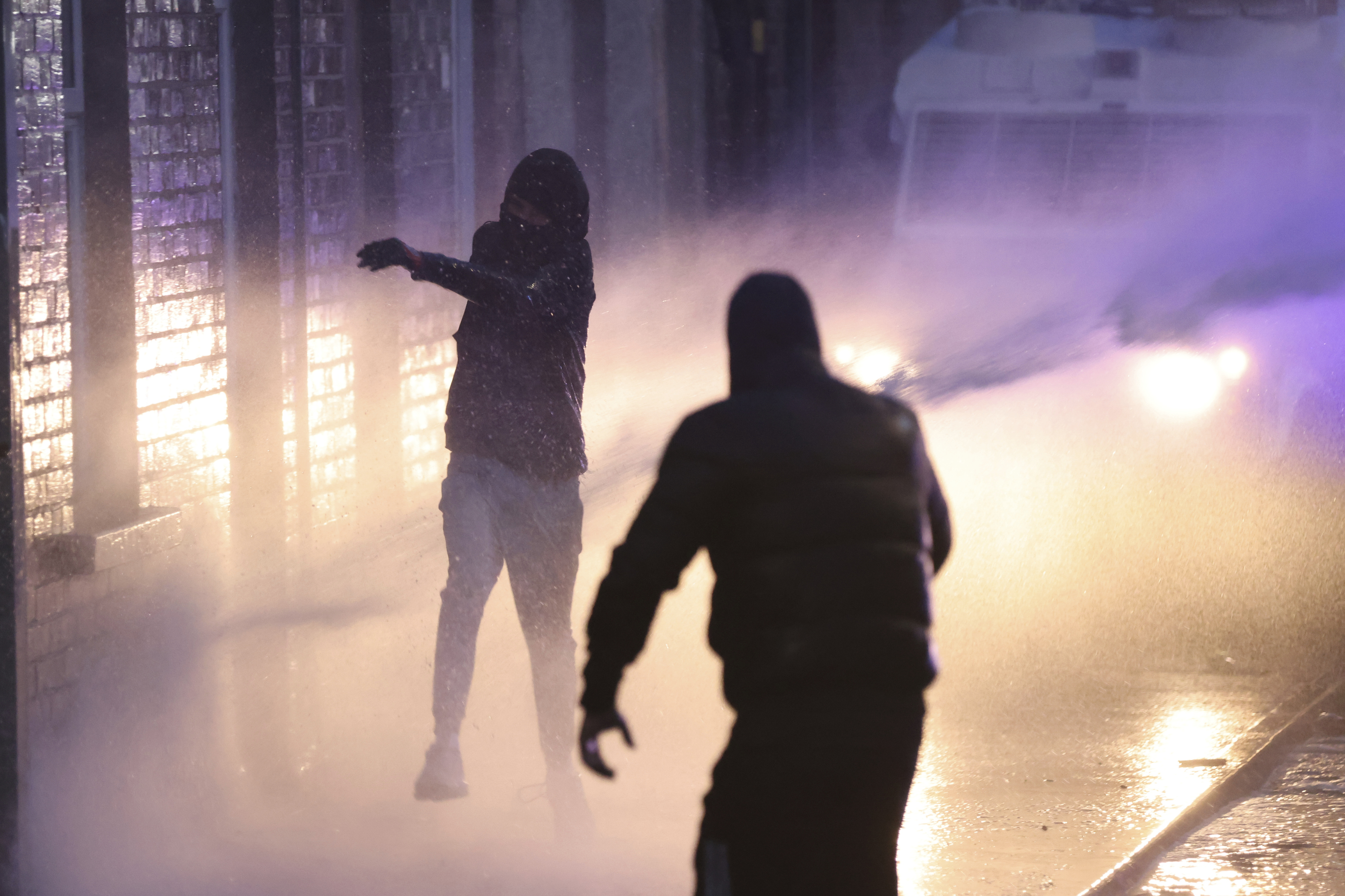 Protesters try to throw items at the police who use water canons to clear them in Ballymena, Northern Ireland.