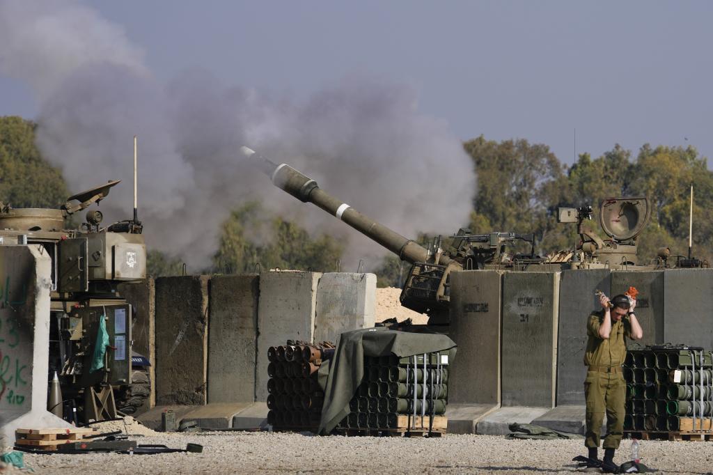 An Israeli soldier covers his ears as an artillery gunner fires into the Gaza Strip from a position in southern Israel,