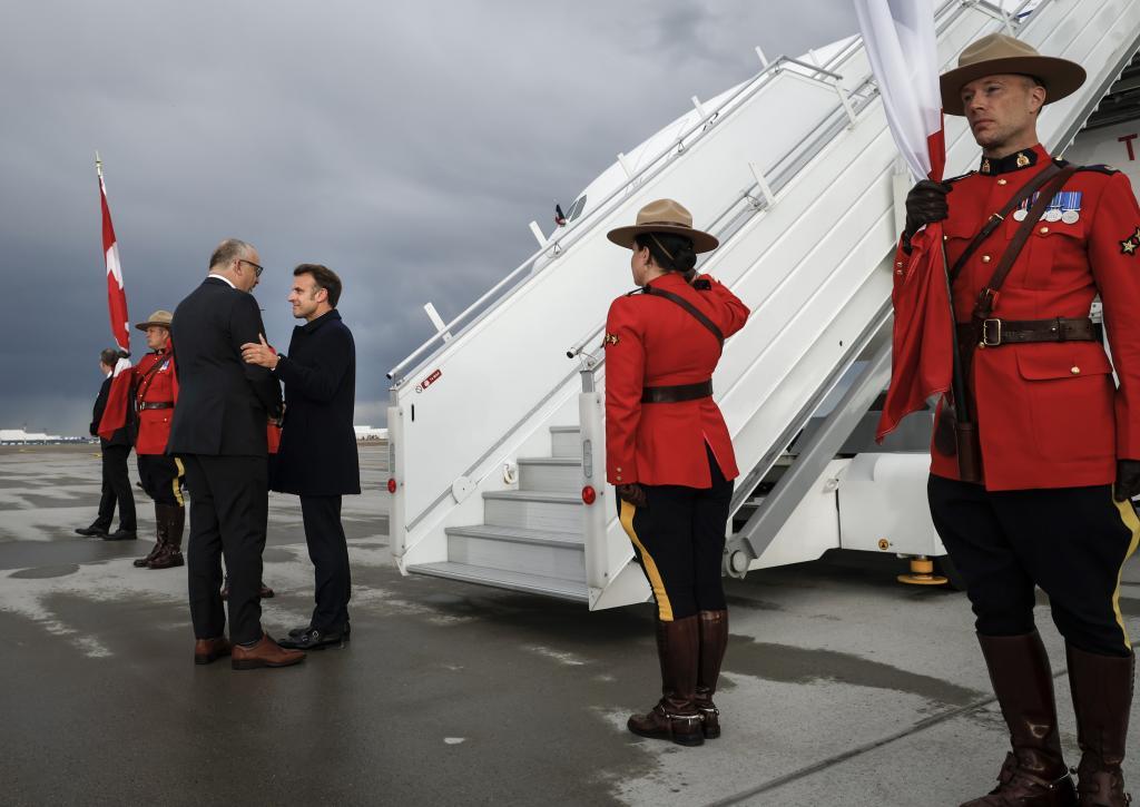 French President Emmanuel Macron, centre, is greeted as he arrives in Calgary