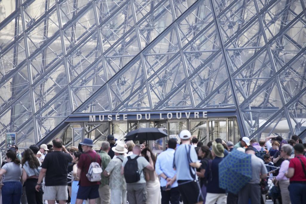 Tourists wait outside the Louvre museum which failed to open on time Monday