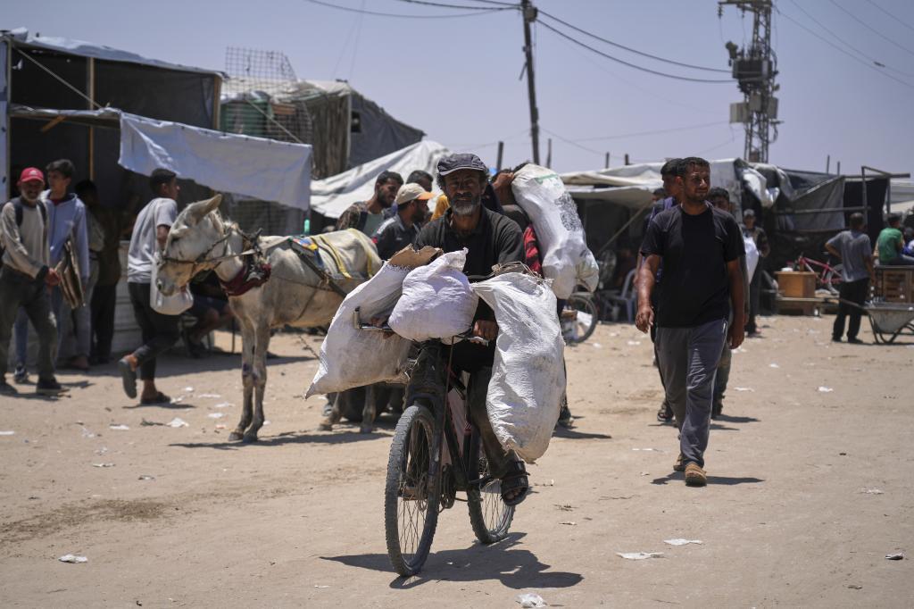Palestinians carry bags containing food and humanitarian aid packages delivered by the Gaza Humanitarian Foundation