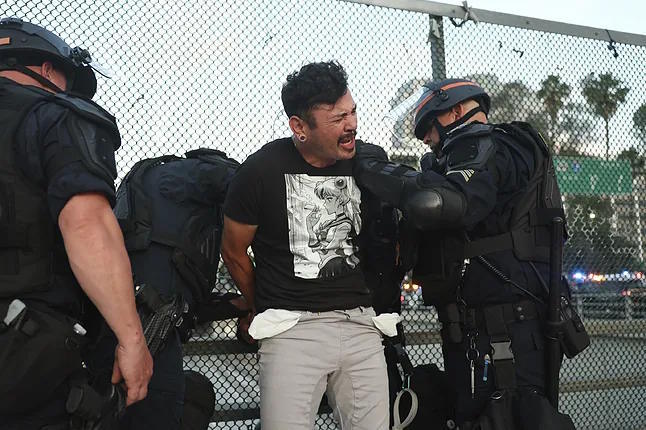 Authorities detain a man during the protests in Los Angeles.