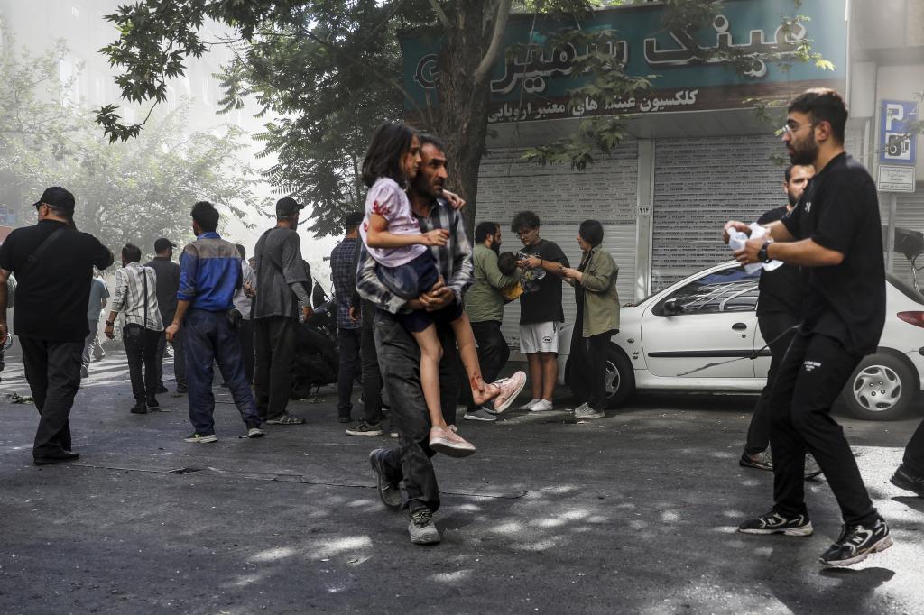 A man carries an injured girl after an explosion in central Tehran.
