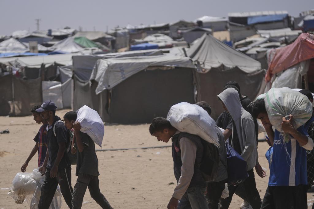 Palestinians carry bags containing food and humanitarian aid packages delivered by the Gaza Humanitarian Foundation
