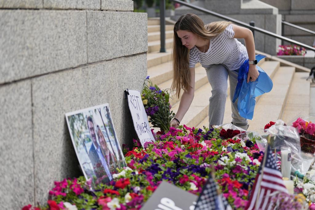 Claire Stein places flowers at a makeshift altar honoring Minnesota State Representative Melissa Hortman and her husband, Mark, at the State Capitol.