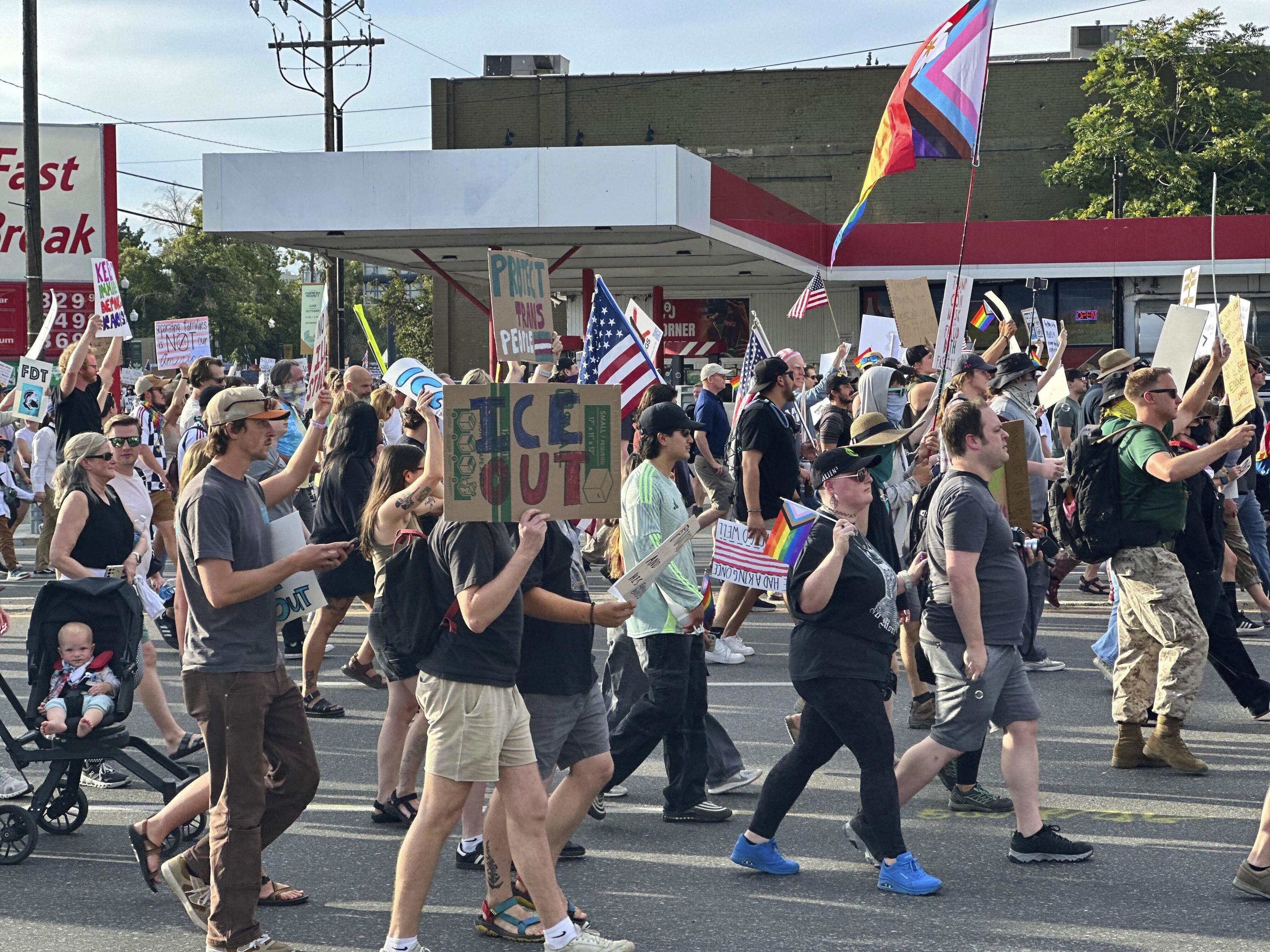Demonstrators carry signs while marching during a "No Kings" protest.