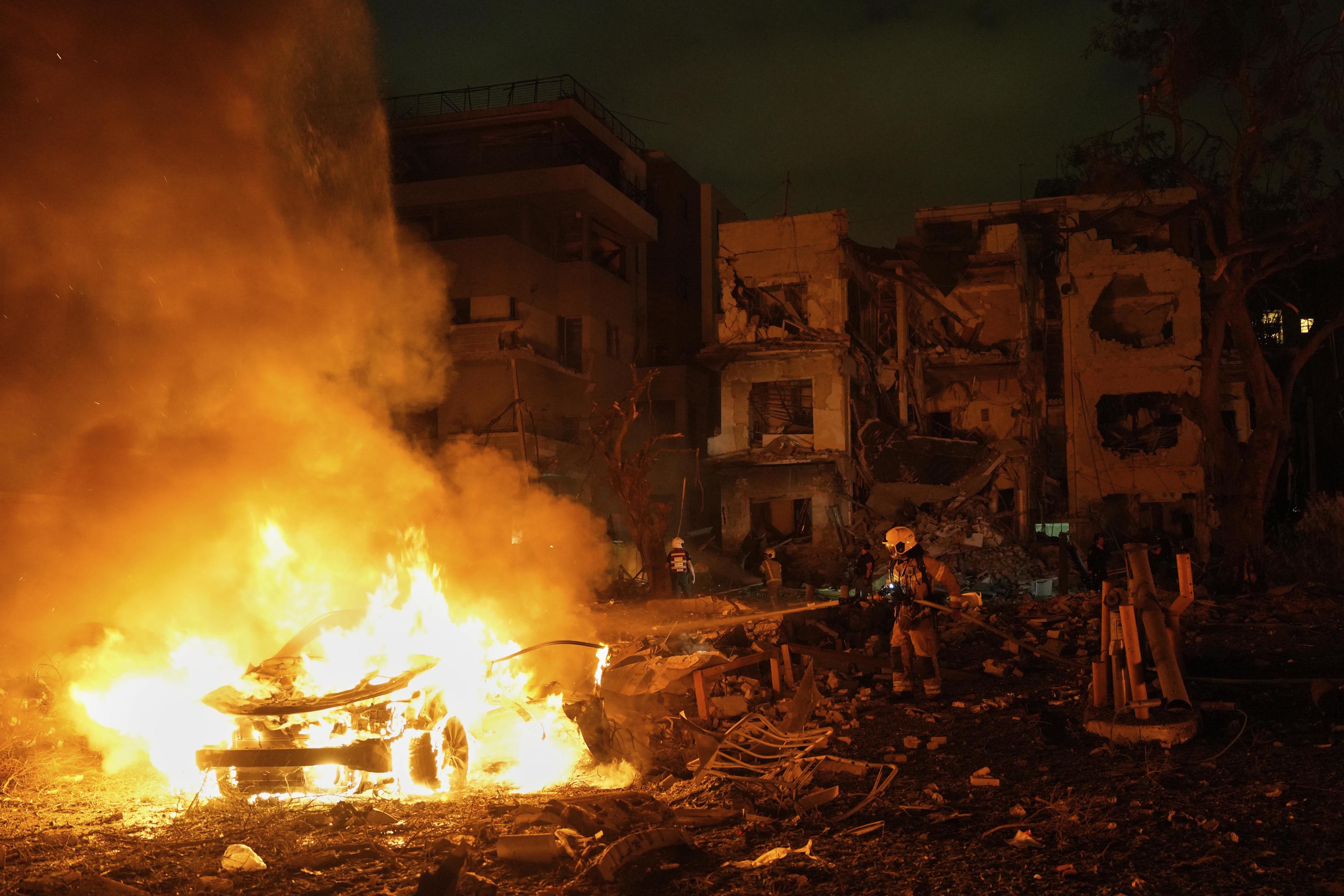 Firefighters extinguish a blaze after a missile launched by Iran hit Tel Aviv.
