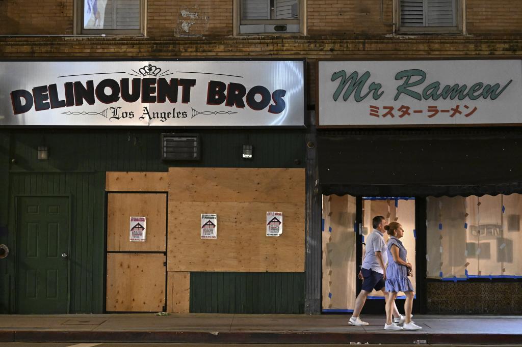 A couple walks past boarded up businesses along 1st St. in Little Tokyo