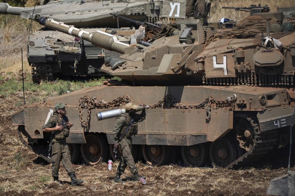 An Israeli soldier carries a shell next to a tank in northern Israel o