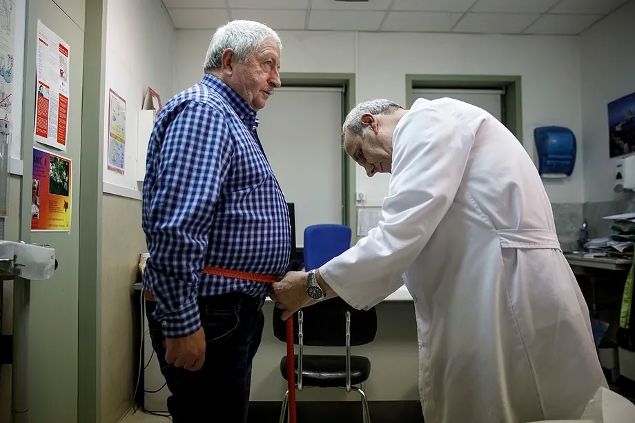 A doctor measures a patient's waist circumference.