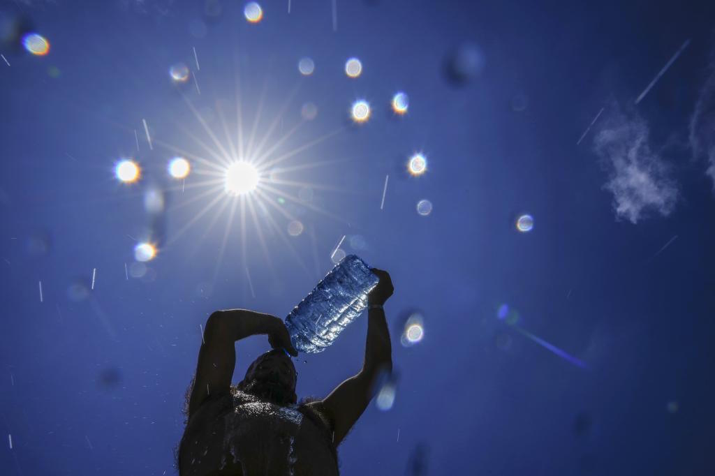 A man pours cold water onto his head to cool off on a sweltering hot day.