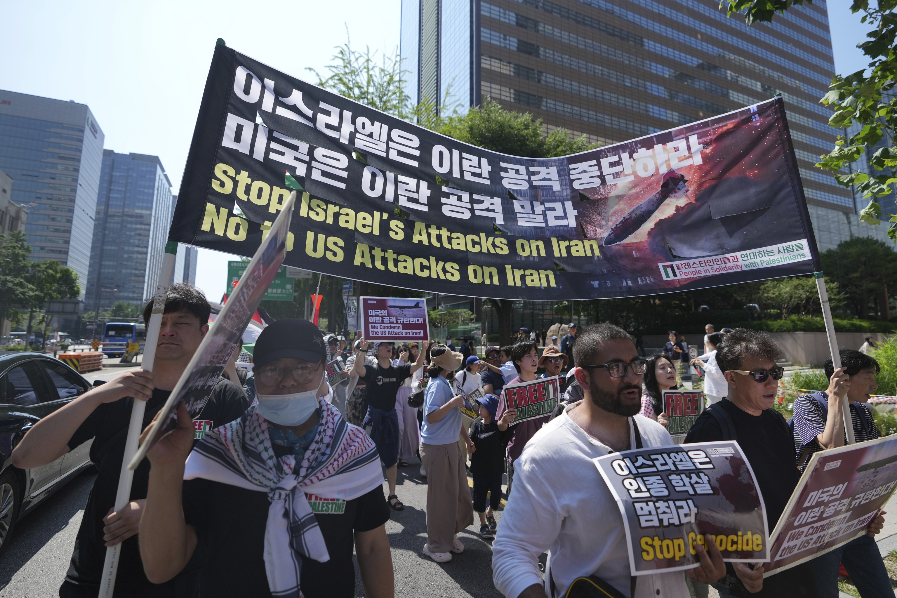 People hold the Iranian flags and signs during a rally demanding to stop the war between Israel and Iran.