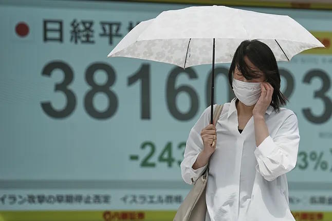 A person walks past one of the panels displaying the Nikkei index in Tokyo.
