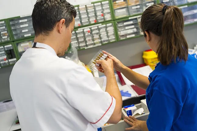 Two healthcare workers prepare the necessary medication to deliver chemotherapy to the patient's home.