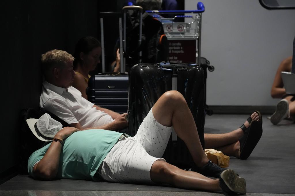 Passengers rest next to their luggage in Rome's Leonardo Da Vinci international airport