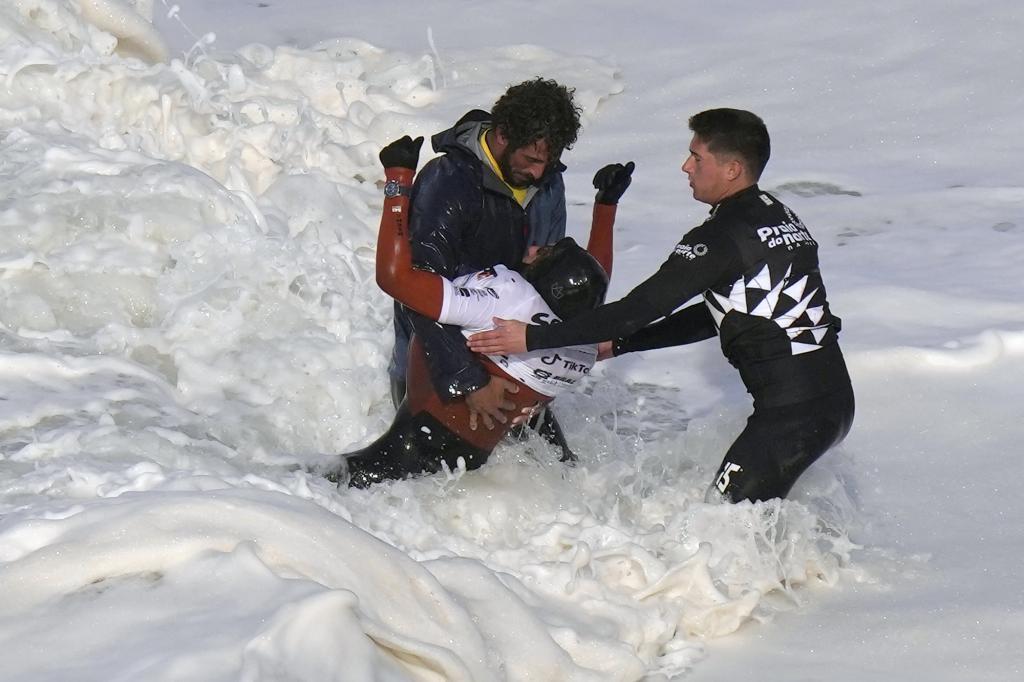 surfer Justine Dupont, from France, center, is carried out of the water after crashing down a wave breaking her ankle during a big wave surfing session at Praia do Norte, or North Beach, in Nazare