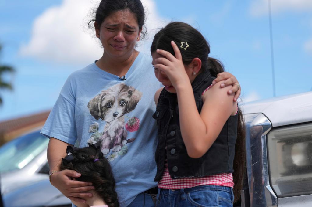 Narel Lopez comforts her daughters after her husband and a son were detained and taken away in a bus following an appearance at immigration court