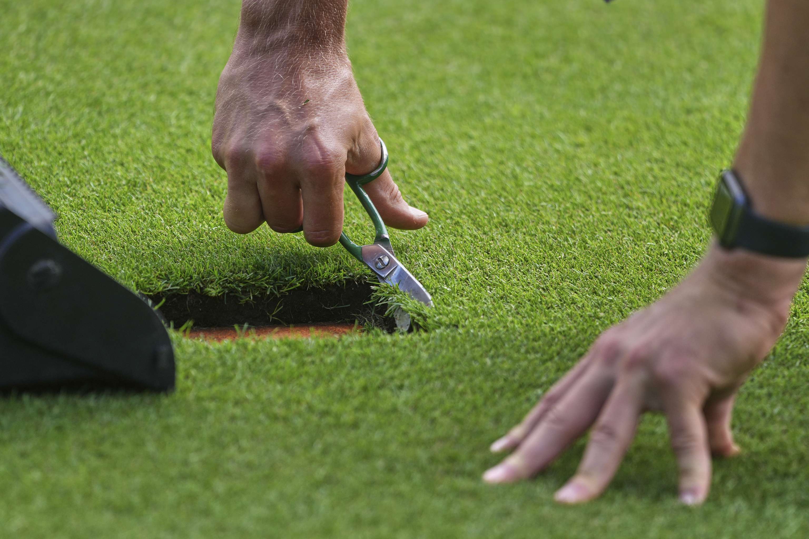 A groundsman works at a court ahead of the Wimbledon Championships at the All England Lawn Tennis and Croquet Club in London.