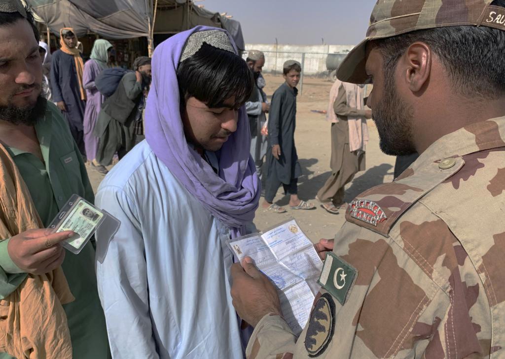 A Pakistani paramilitary soldier checks travel documents of an Afghan