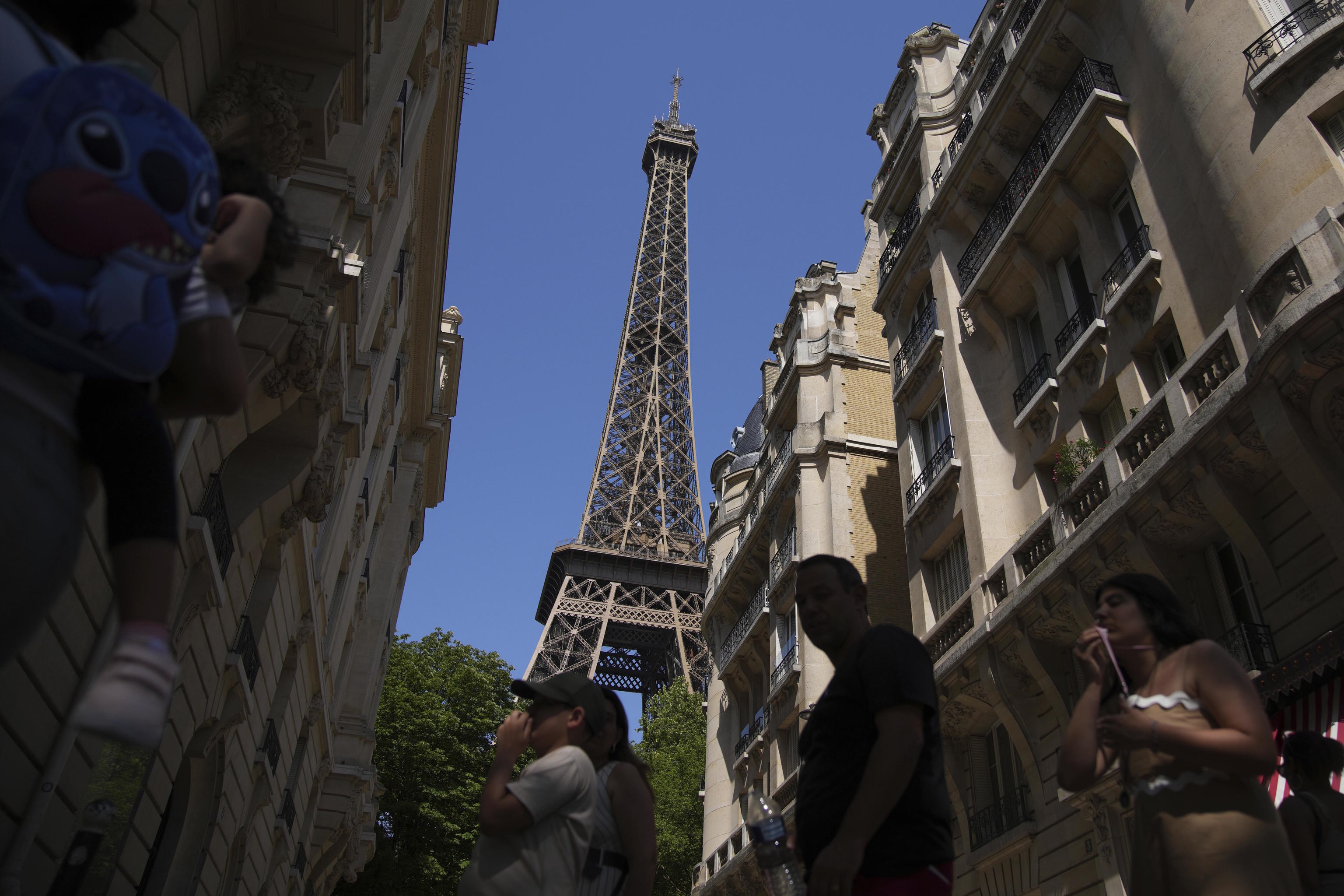 Tourists walk past the Eiffel Tower during a heat wave.