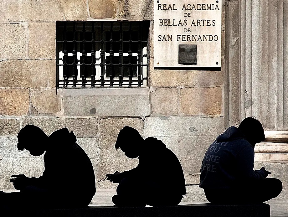 Three young people use their mobile phones.