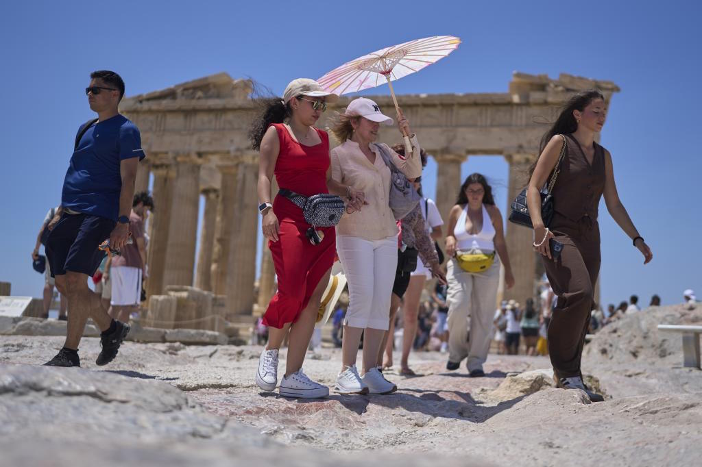 Tourists walk past the ancient Parthenon temple on the Acropolis.